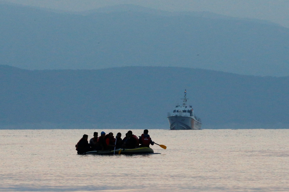 Migrants in a dinghy paddle their way on the Mediterranean Sea to attempt crossing to the Greek island of Kos as a Turkish Coast Guard ship patrols off the shores off Bodrum Sept 19, 2015. Reuters/Umit Bektas