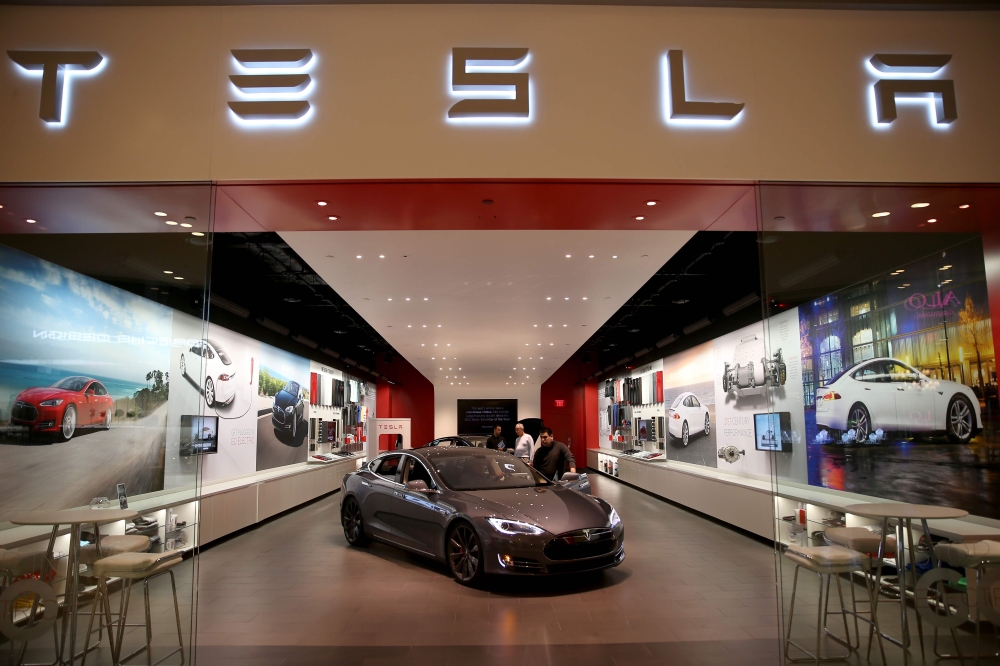 In this file photo taken on February 19, 2014, people look at a Tesla Motors vehicle on the showroom floor at the Dadeland Mall in Miami. AFP/Getty Images North America/Joe Raedle
