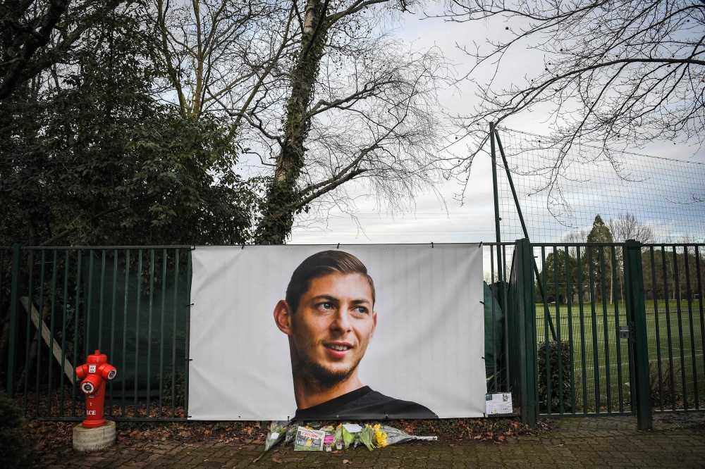 Flowers candles are left with front page of French a daily newspaper reading The disappearance of a warrior next to a portrait of Emiliano Sala in front of the entrance of the FC Nantes (AFP/Loic Venance) 