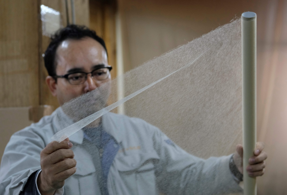 This picture taken on March 15, 2019 shows Hidaka Washi president Hiroyoshi Chinzei, a fourth-generation traditional paper maker, displaying the world's thinnest paper at his factory in Hidaka, Kochi prefecture, some 640 kilometres (400 miles) southwest o