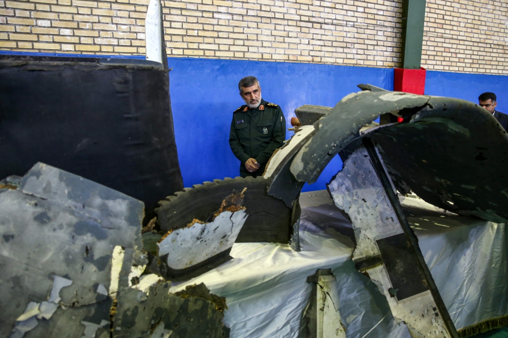 General Amir Ali Hajizadeh (C), Iran's Head of the Revolutionary Guard's aerospace division, looks at the debris from a downed US drone reportedly recovered within Iran's territorial waters and put on display by the Revolutionary Guard in the capital Tehr