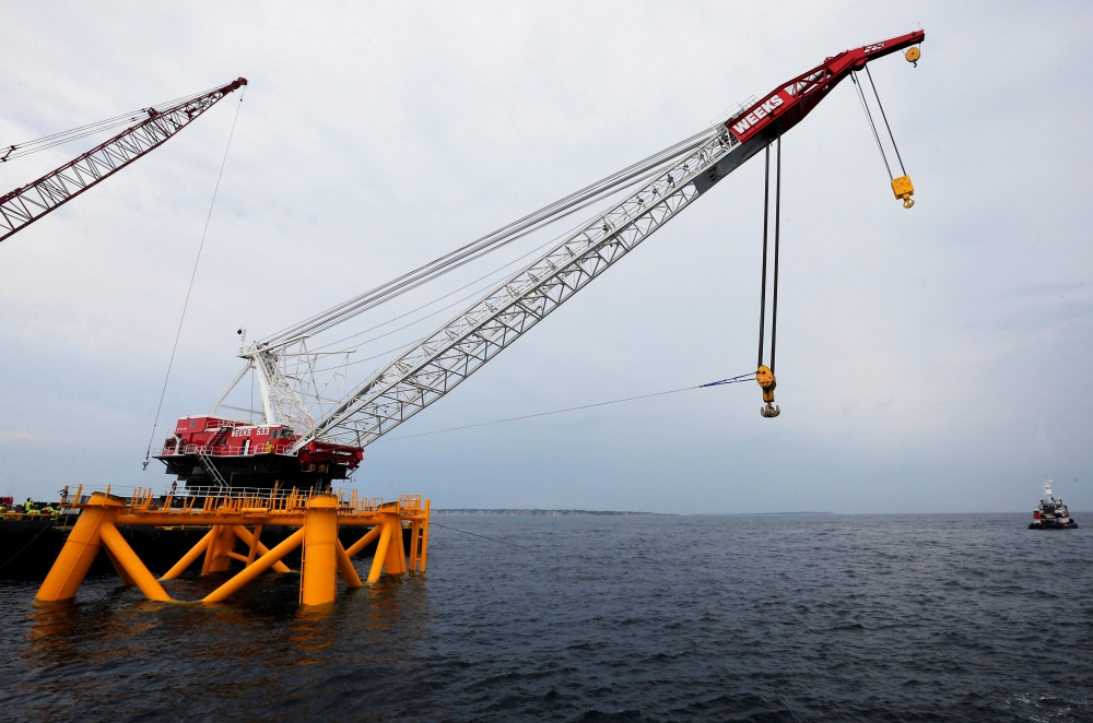 A crane hangs over the first jacket installed to support a turbine for a wind farm in the waters of the Atlantic Ocean off Block Island, Rhode Island July 27, 2015.  Reuters/Brian Snyder