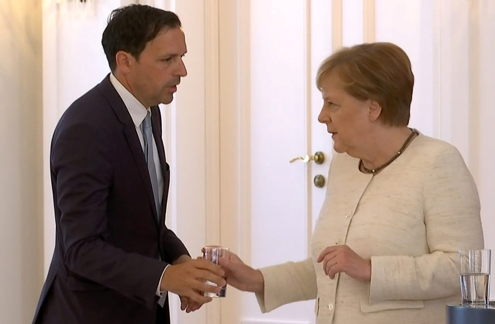 German Chancellor Angela Merkel receives water as she was seen shaking meeting President Frank-Walter Steinmeier in Berlin, Germany, June 27, 2019, her second shaking bout within two weeks. REUTERS/Reuters TV
