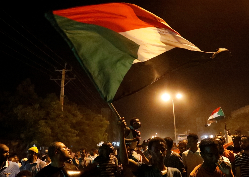 FILE PHOTO: Sudanese people, seeking to revive a push for civilian rule in ongoing tumult since the overthrow of former President Omar al-Bashir more than two months ago, chant slogans and wave Sudanese flags during a demonstration in Khartoum, Sudan, Jun
