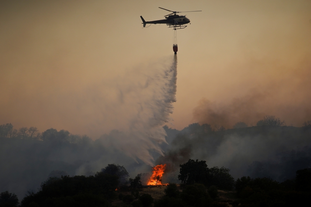 A helicopter drops water over a wildfire near the city of Toledo, Spain June 28, 2019. REUTERS/Juan Medina