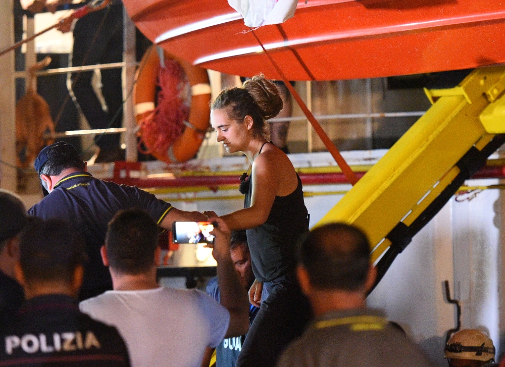 Carola Rackete, the 31-year-old Sea-Watch 3 captain, is escorted off the ship by police and taken away for questioning, in Lampedusa, Italy June 29, 2019. (REUTERS/Guglielmo Mangiapane)