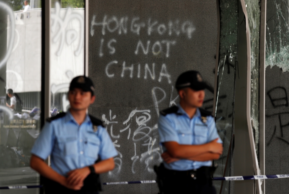 Policemen stand in front of graffiti on the walls of the Legislative Council, a day after protesters broke into the building in Hong Kong, China July 2, 2019. REUTERS/Jorge Silva