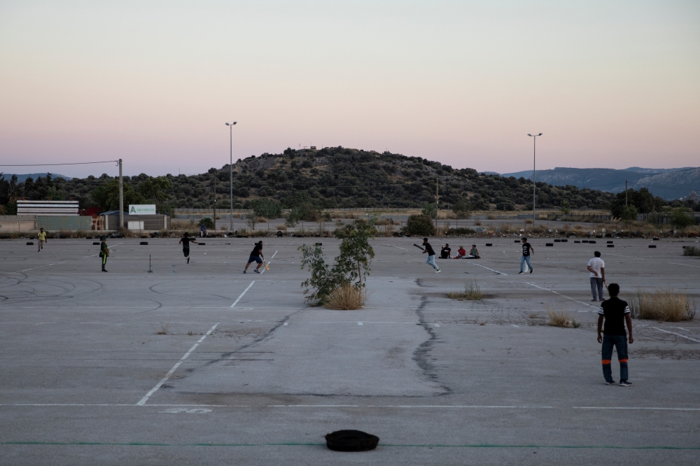 Pakistani men living in Greece play a game of tape-ball cricket in a disused parking lot for trucks in an industrial area in Elefsina, Greece, June 30, 2019. REUTERS/Alkis Konstantinidis