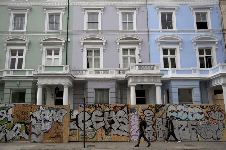 People walk past boarded-up houses ahead of the Notting Hill Carnival in London, August 27, 2016. Reuters/Neil Hall