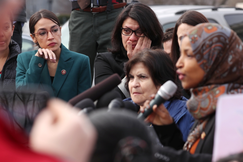Alexandria Ocasio-Cortez and Rashida Tlaib wipe away tears as Ilhan Omar talks about her own experience as a refugee in Washington, February 7, 2019/ Reuters/Jonathan Ernst