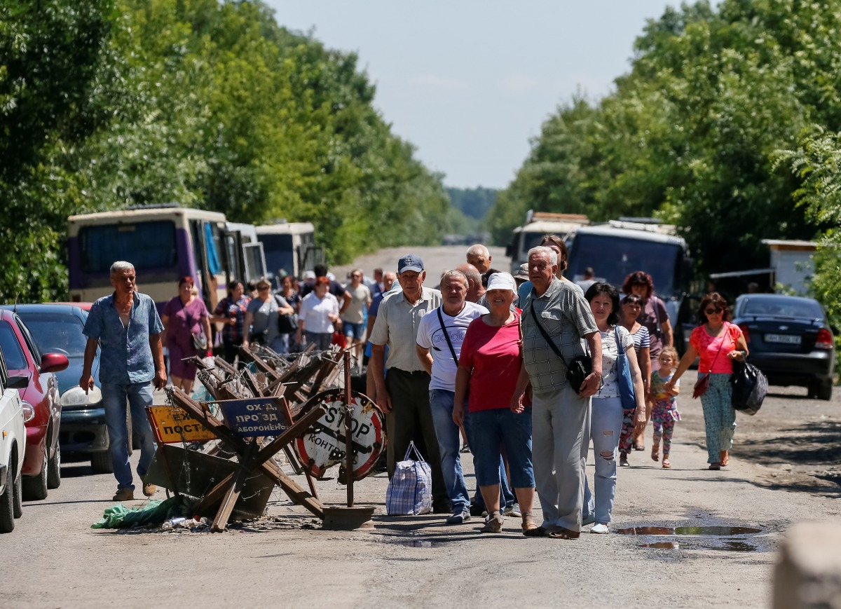 People stand near a checkpoint before crossing the contact line between pro-Russian rebels and Ukrainian troops in Mayorsk, Ukraine July 3, 2019.  Reuters/Gleb Garanich