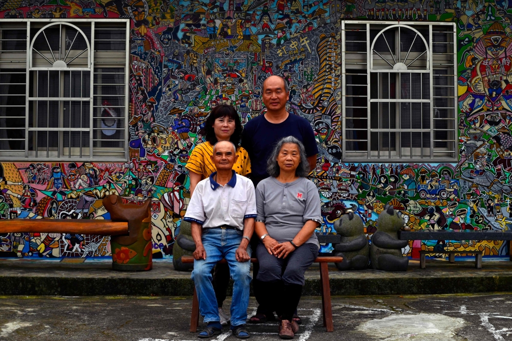 This picture taken on May 21, 2019 shows Hakka graffiti artist Wu Tsun-hsien (top R) posing with his family in front of their home in the Taiwanese village of Ruan Chiao. AFP /Sam Yeh