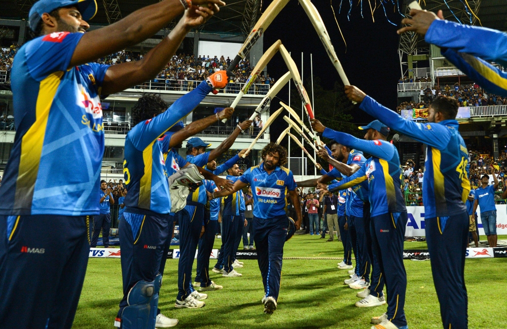 Sri Lankan cricketer Lasith Malinga (C) receives a farewell from his teammates after declaring his retirement from One Day International (ODI) cricket at the start of the first One Day International (ODI) cricket match between Sri Lanka and Bangladesh at 