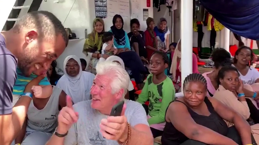U.S. actor Richard Gere talks to a rescued migrant aboard Open Arms rescue boat at Mediterranean sea, in this screen grab taken from a video, August 9, 2019. (Open Arms/Reuters TV via REUTERS)