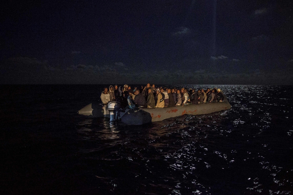 FILE PHOTO: Migrants onboard an inflatible boat wait for being rescued off the coast of Libya by Proactiva Open Arms organisation.  AFP / Olmo CALVO