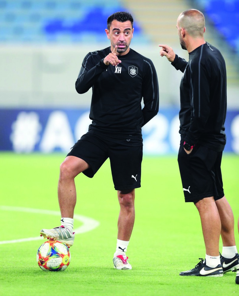 Al Sadd’s coach Xavi Hernandez  speaks with a club official during a training session.