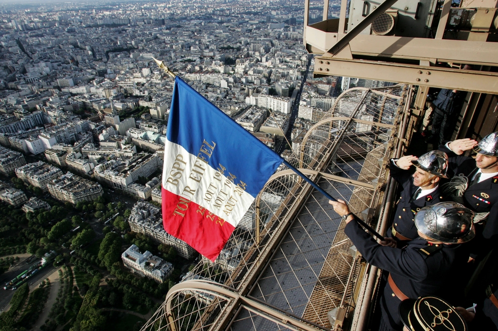 FILE PHOTO: Paris firemen display a French national flag on the balcony of the Eiffel Tower in Paris, in memory of their 1944 colleagues who did it on the day Paris was liberated from Nazi occupation. AFP / PIERRE VERDY
