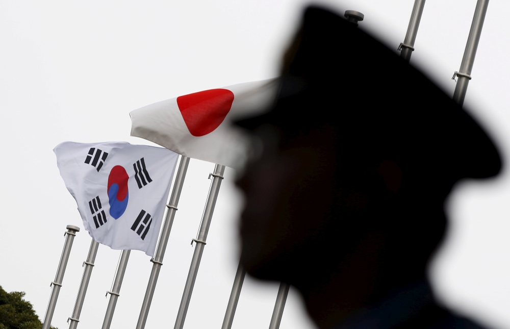 A police officer stands guard near Japan and South Korea national flags at hotel, where South Korean embassy in Japan is holding the reception to mark the 50th anniversary of normalisation of ties between Seoul and Tokyo, in Tokyo June 22, 2015. Reuters/T