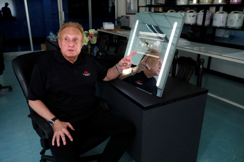 Larry Sloven shows a touch mirror that can be used as a tablet, at a factory in Bangkok, Thailand July 22, 2019. Reuters/Soe Zeya Tun