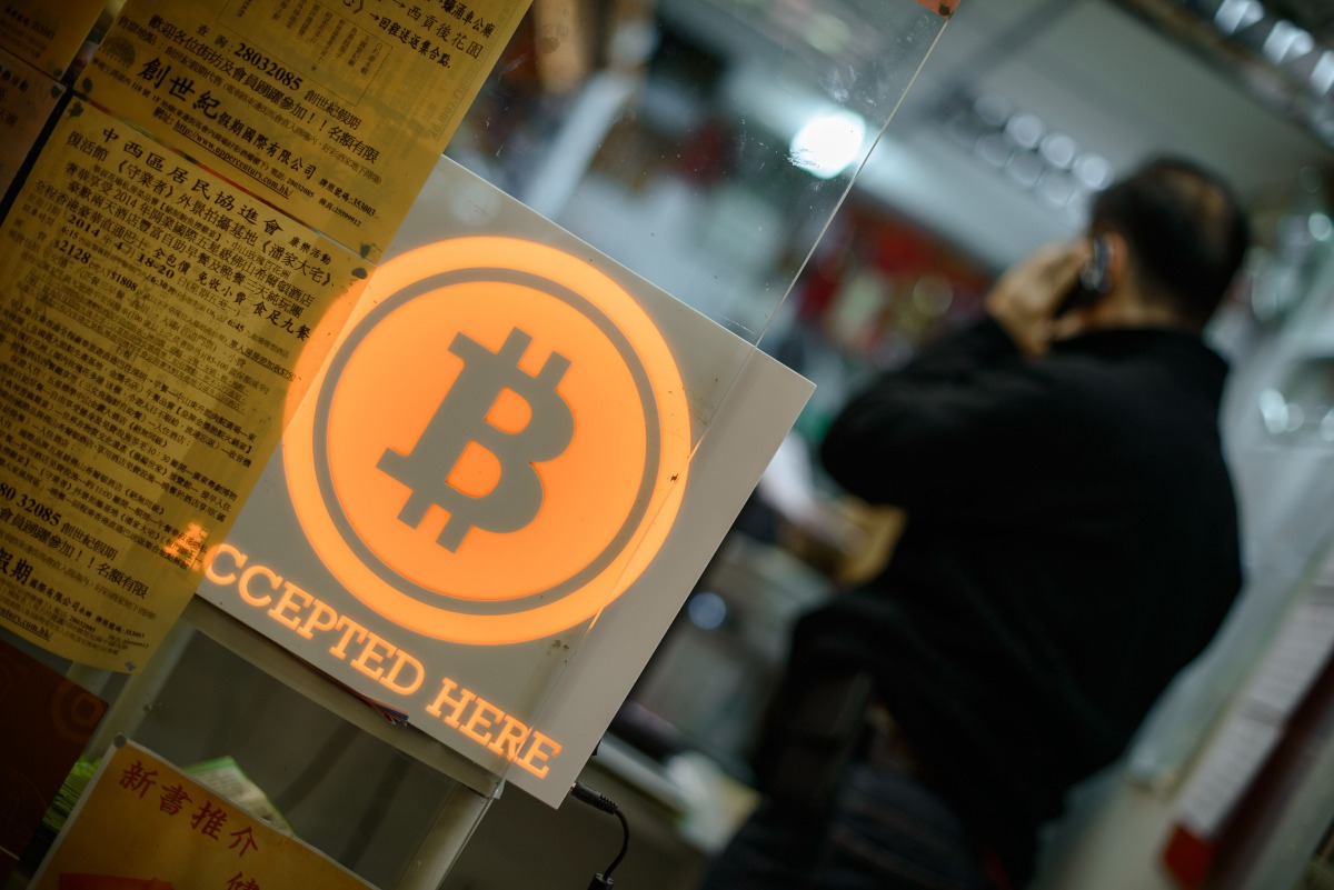 This file picture taken on February 28, 2014 shows a man talking on a mobile phone in a shop displaying a bitcoin sign during the opening ceremony of the first bitcoin retail shop in Hong Kong. AFP