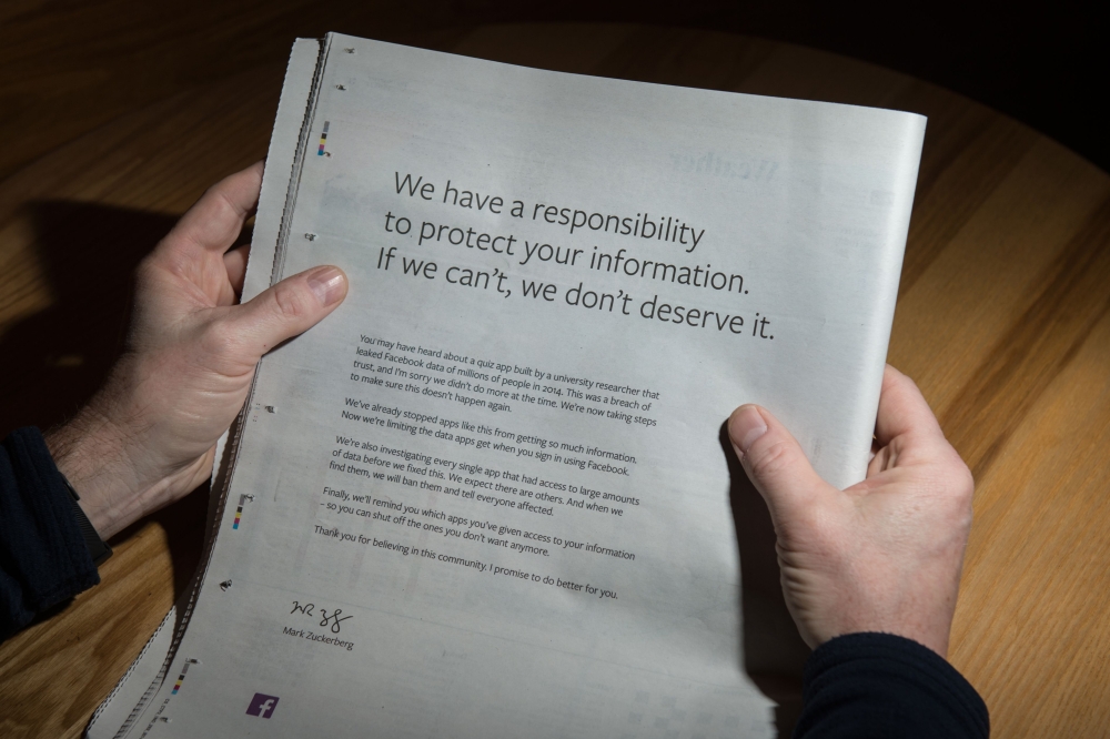 A man reads advertisement taken out by Mark Zuckerberg of Facebook to apologise for the leak of personal data on the backpage of a newspaper in Ripon, England, on March 25, 2018. AFP/Oli Scarff