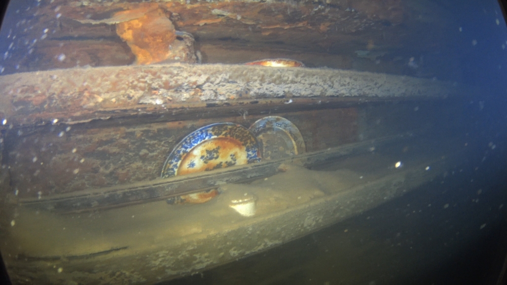Plates and other artifacts sitting on shelves next to a mess table where a group of lower-ranking crew members would have taken their meals on HMS Terror, underwater in Terror Bay, off King William Island, Nunavut.  AFP/ Parks Canada Agency/Ryan Harris
