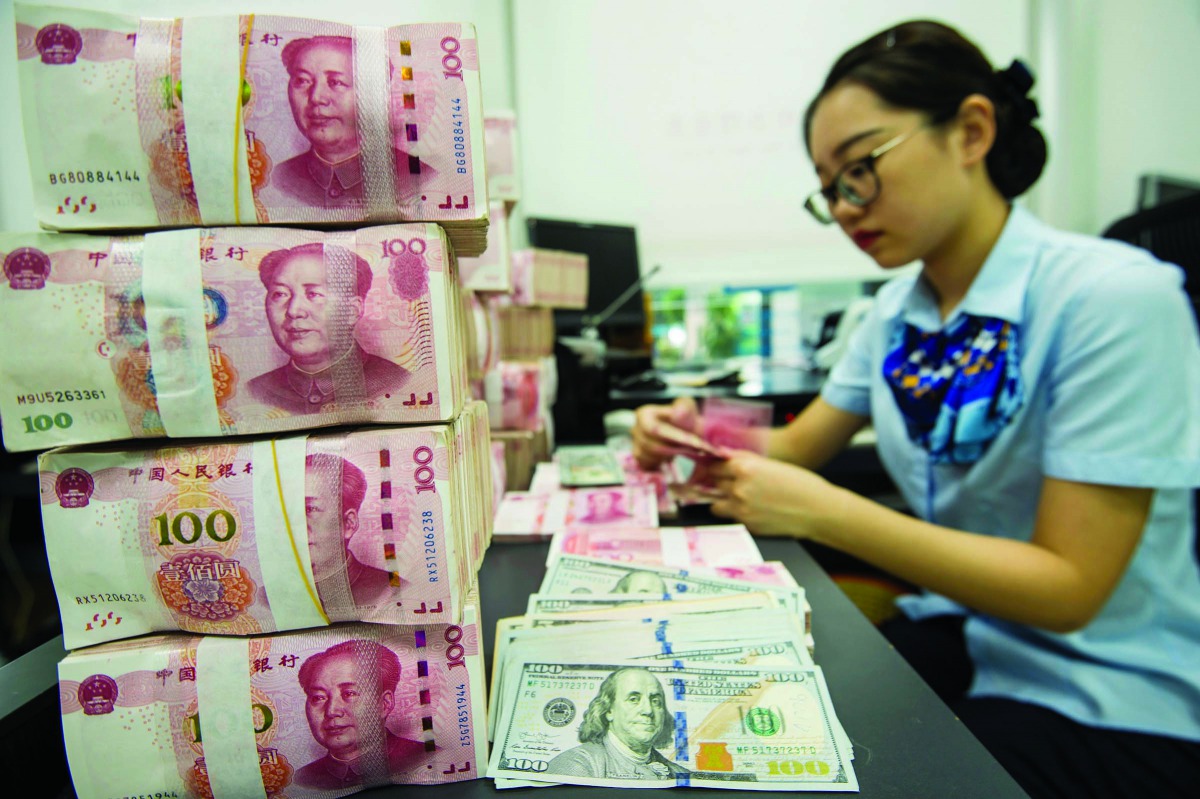 A Chinese bank employee counts 100-yuan notes and US dollar bills at a bank counter in Nantong in China's eastern Jiangsu province on August 28, 2019. AFP