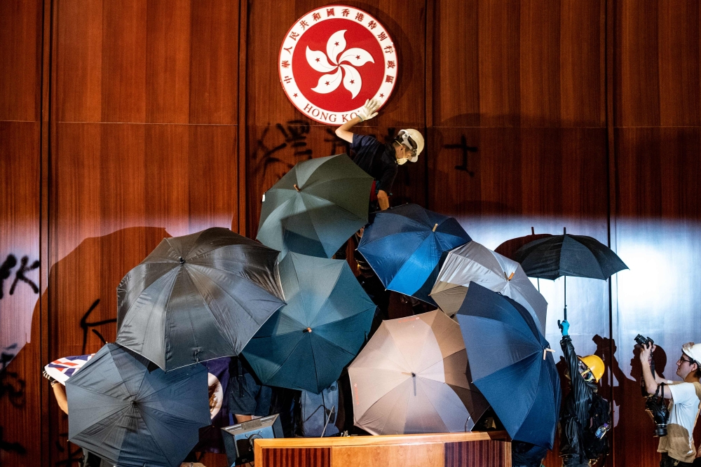 A protester defaces the Hong Kong emblem after they broke into the government headquarters in Hong Kong on July 1, 2019 on 22nd anniversary of the city handover from Britain to China. AFP /Philip Fong