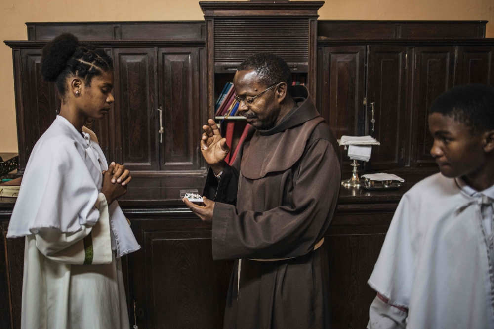 Vicar at the Our Lady of the Rosary Cathedral, Father Alfredo Manhica (C), blesses a Rosary in Beira, central Mozambique on August 20, 2019. AFP / Marco Longari 