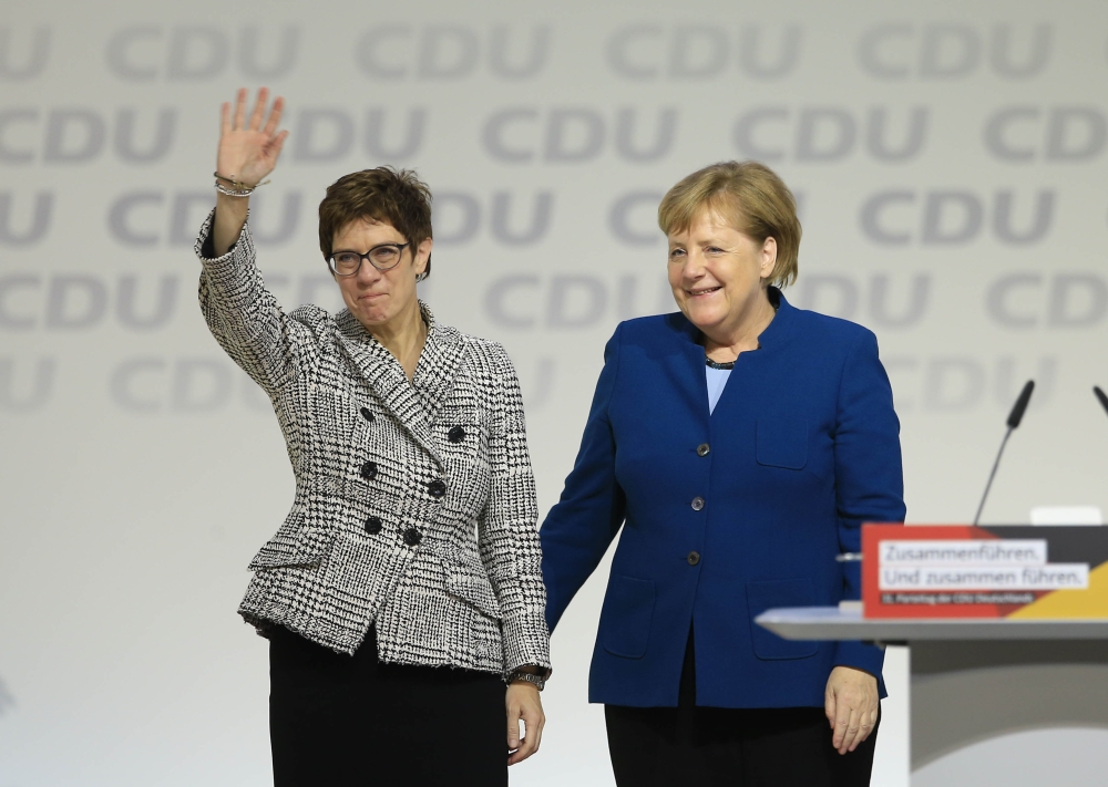 Annegret Kramp-Karrenbauer greets delegates while she stands next to Angela Merkel after she has been elected as new CDU party leader in Hamburg on December 7, 2018. Abdülhamid Ho?ba?/ Anadolu Agency