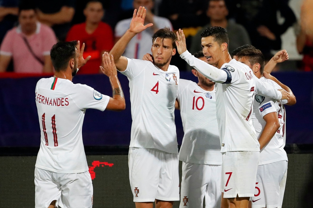 (FromL) Portugal's midfielder Bruno Fernandes, Portugal's defender Ruben Dias and Portugal's forward Cristiano Ronaldo celebrate a goal during the EURO 2020 football qualification match between Serbia and Portugal in Belgrade, Serbia, on September 7, 2019
