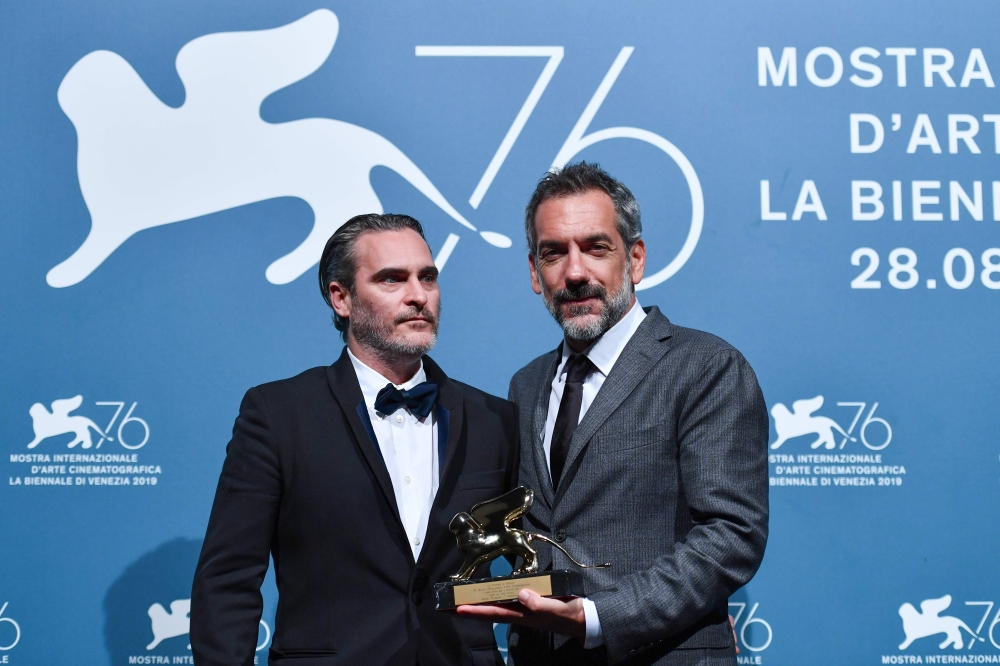 US director Todd Phillips (R), flanked by US actor Joaquin Phoenix, holds the Golden Lion award for Best Film he received for the movie 