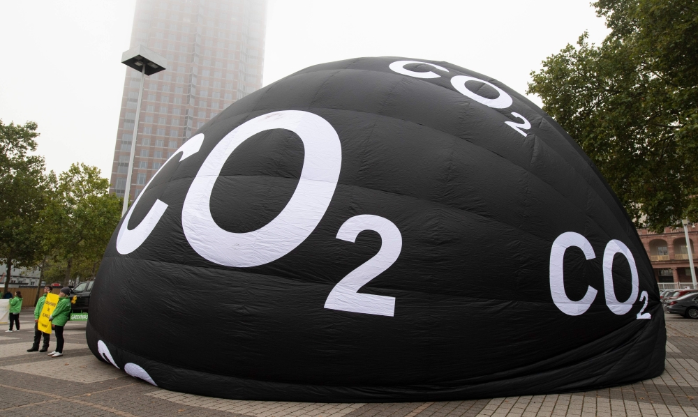 Greenpeace activists inflate a giant balloon reading 