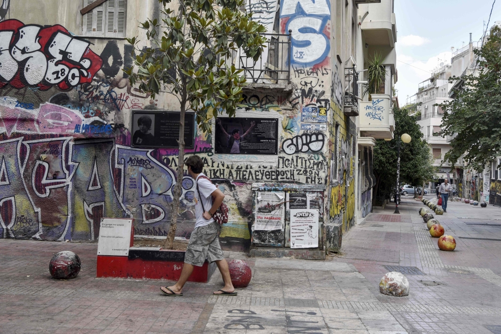 A man walks past a memorial at a spot where a 15-years old student was killed by police in 2008, sparking unrest in greece, in Athens' historic district of Exarchia on September 13, 2019. AFP / LOUISA GOULIAMAKI