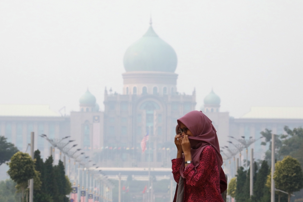 A woman covers her face with a scarf in front of the Malaysia's Prime Minister's office, which is shrouded in haze, in Putrajaya, Malaysia, September 17, 2019. REUTERS/Lim Huey Teng