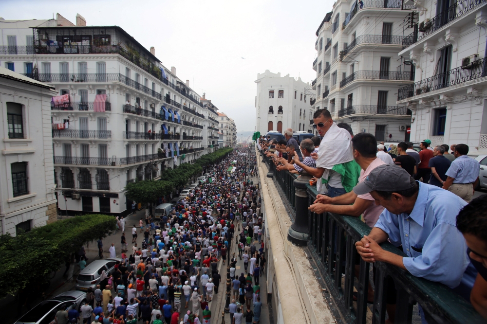 People watch demonstrators shouting slogans during a protest to reject the Algerian election announcement for December, in Algiers, Algeria September 20, 2019. Reuters/Ramzi Boudina
 