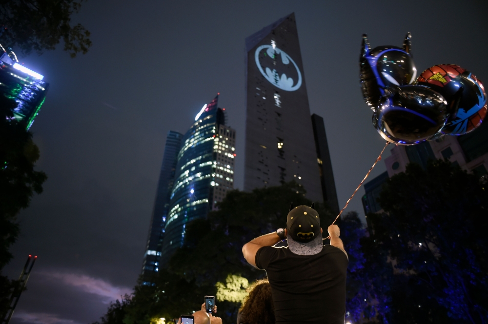 A fan man looks at Batman's symbol projected over the Reforma Tower on the 80th anniversary of US comics fictional superhero in Mexico City, on September 21, 2019. / AFP / ALFREDO ESTRELLA