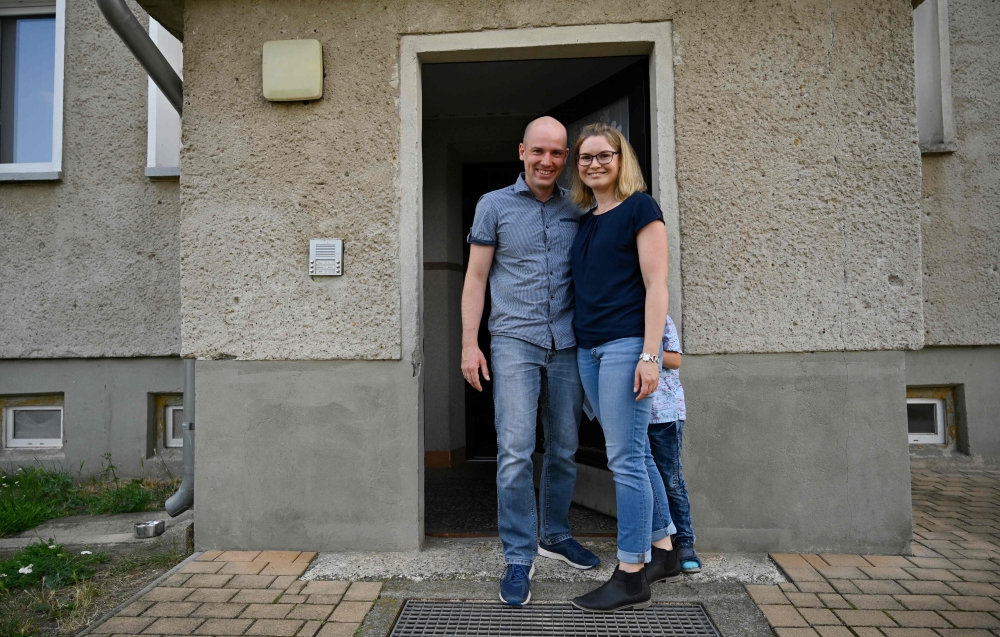 Carsten and Peggy Hoffmann pose outside their temporary flat in Glindenberg, near Magdeburg on August 16, 2019. AFP / John John MacDougall