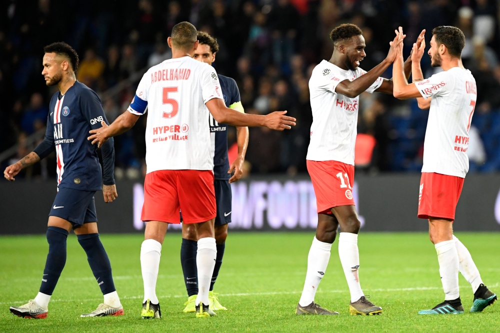 Reims' French midfielder Boulaye Dia (2ndR), Reims' Moroccan defender Yunis Abdelhamid (2ndL) and Reims' French midfielder Xavier Chavalerin (R) celebrate their victory past Paris Saint-Germain's Brazilian forward Neymar at the end of the French L1 footba