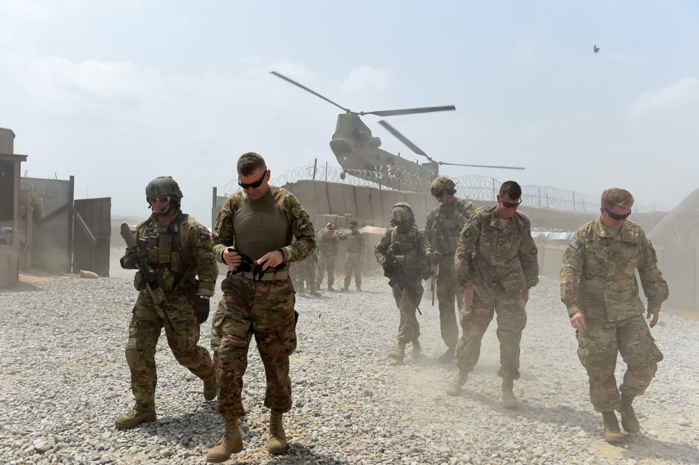 US soldiers walk as a NATO helicopter flies overhead in the Khogyani district in the Afghan eastern province of Nangarhar on August 12, 2015. AFP/Wakil Kohsar