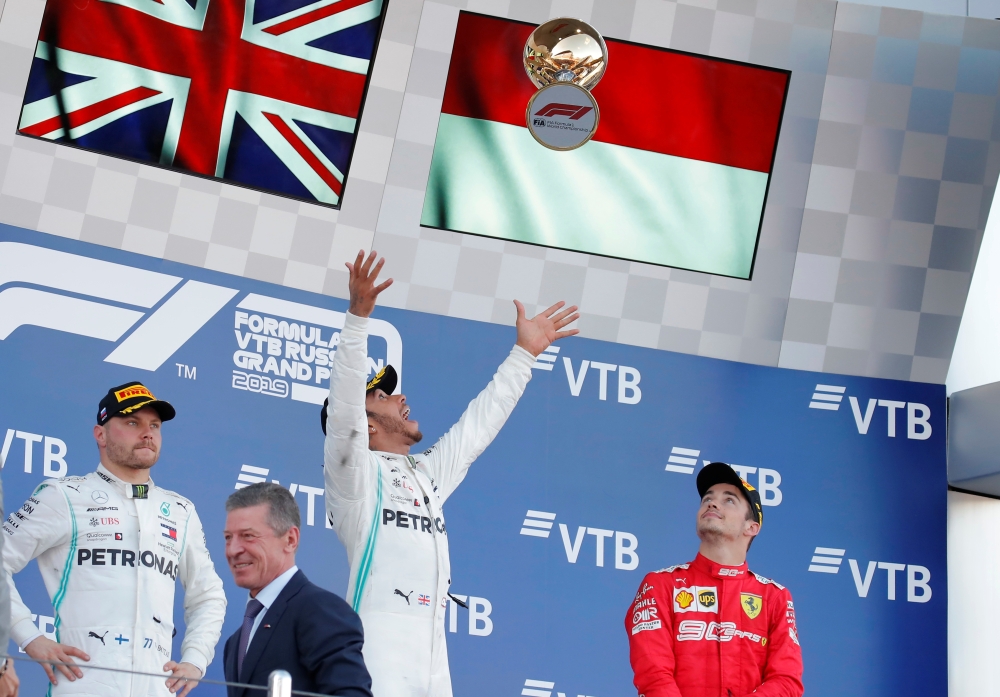 Mercedes' Lewis Hamilton celebrates with a trophy on the podium after winning the race alongside second placed Mercedes' Valtteri Bottas and third placed Ferrari's Charles Leclerc REUTERS/Maxim Shemetov