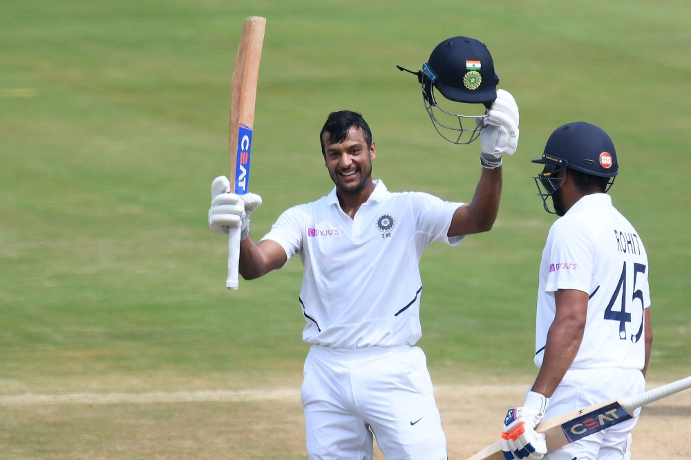 Indian cricketer Mayank Agarwal (L) raises his bat after scoring a century (100 runs) during the second day's play of the first Test match between India and South Africa at the Dr. Y.S. Rajasekhara Reddy ACA-VDCA Cricket Stadium in Visakhapatnam on Octobe