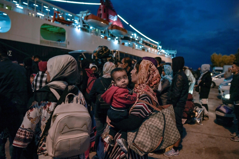 Refugees and migrants wait to be transferred to a camp in northern Greece, after their arrival from the island of Lesbos to the port of Piraeus near Athens early on October 7, 2019.   AFP / LOUISA GOULIAMAKI