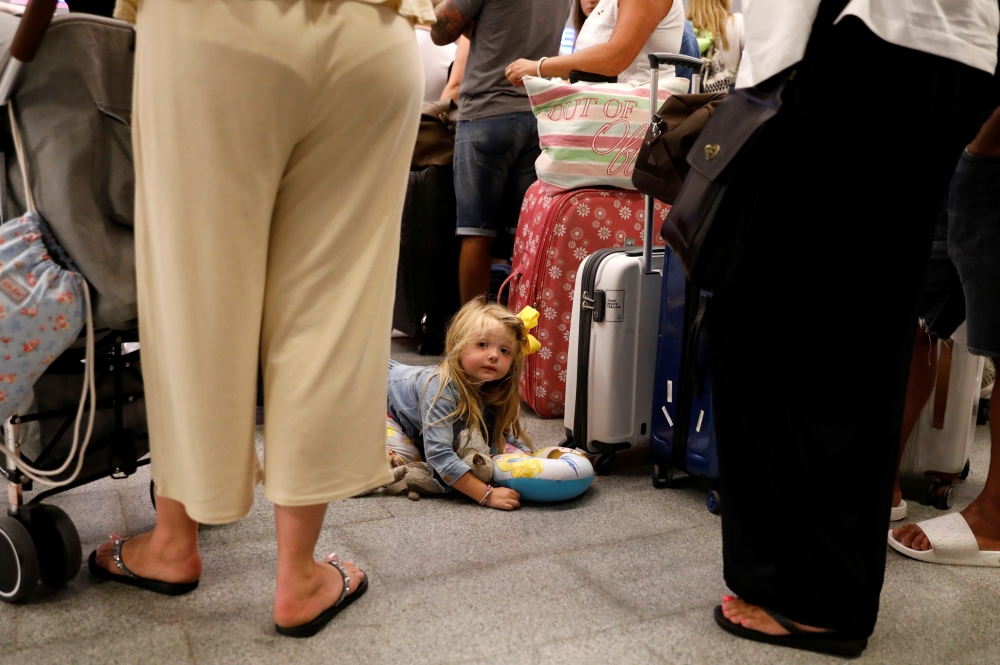 A 3 years old British passenger Indie Robertson lays on the ground as her family queue up at a check-in service at Dalaman Airport after Thomas Cook collapse in Dalaman, Turkey, September 24, 2019. Reuters / Umit Bektas