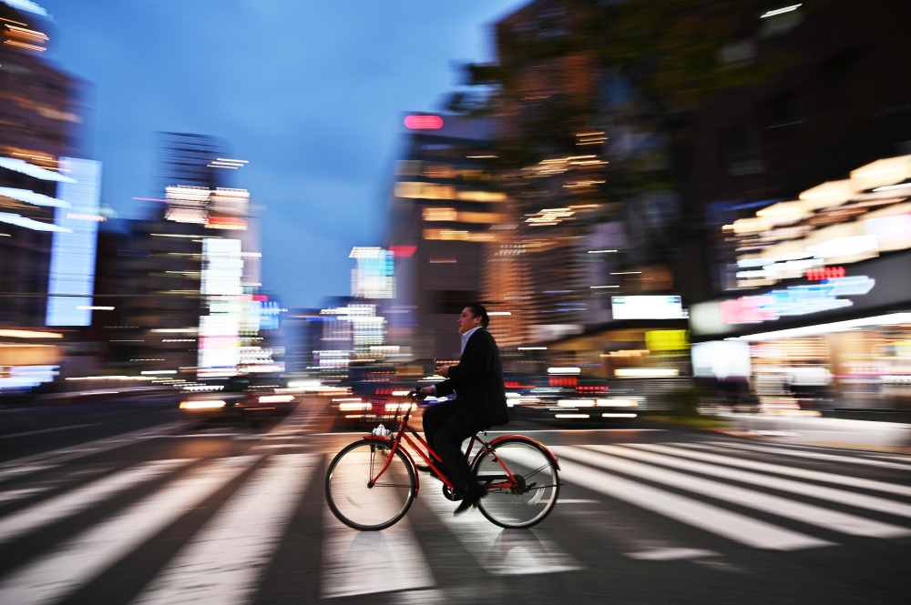 A man rides his bicycle at night in Tokyo on April 22, 2019. AFP / Charly Triballeau