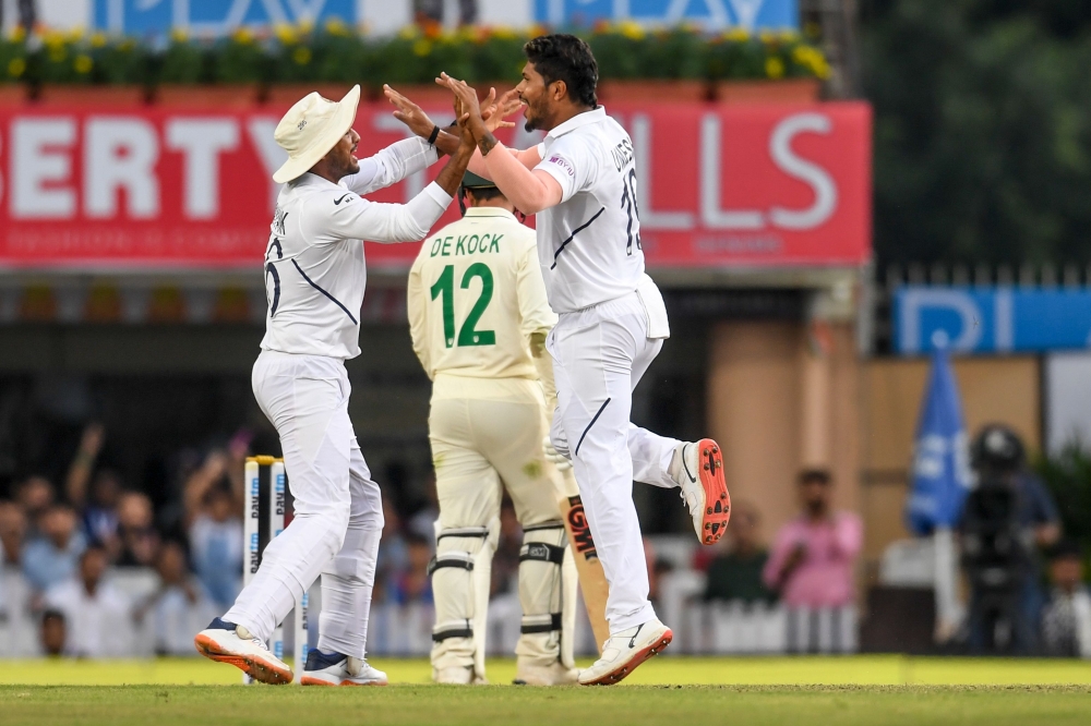 India's Umesh Yadav (R) celebrates with teammate Mayank Agarwal (L) as South Africa's Quinton de Kock (C) walks back to the pavilion after being dismissed during the second day of the third and final Test match between India and South Africa at the Jharkh