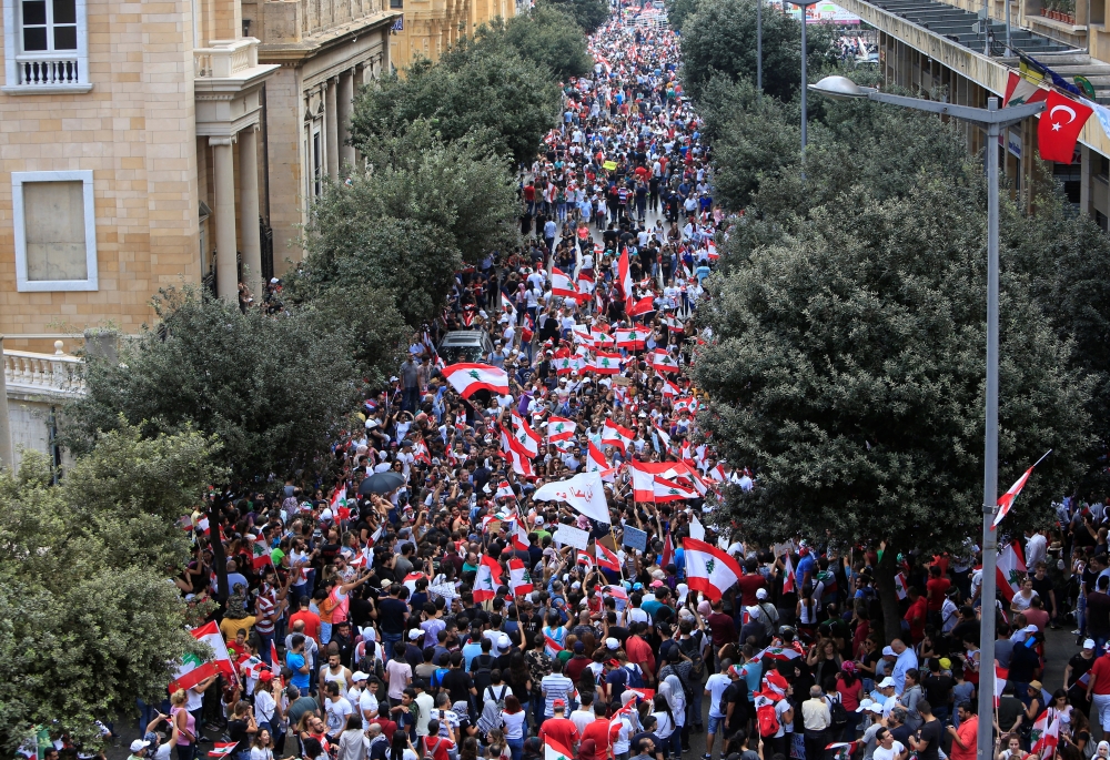 Demonstrators carry national flags and banners during an anti-government protest in downtown Beirut, Lebanon October 20, 2019. REUTERS/Ali Hashisho