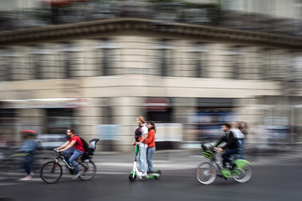 In this file photo taken on September 13, 2019 a couple rides an electric scooter in Paris. AFP / Martin Bureau 