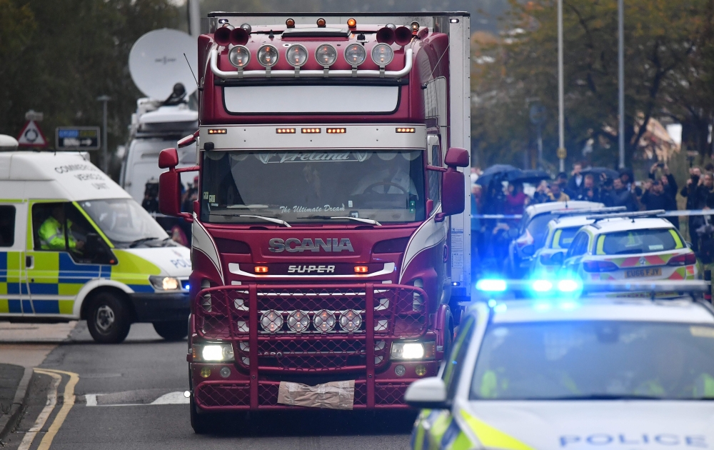 Police officers drive away a lorry (C) in which 39 dead bodies were discovered sparking a murder investigation at Waterglade Industrial Park in Grays, east of London, on October 23, 2019. (AFP / Ben STANSALL)
