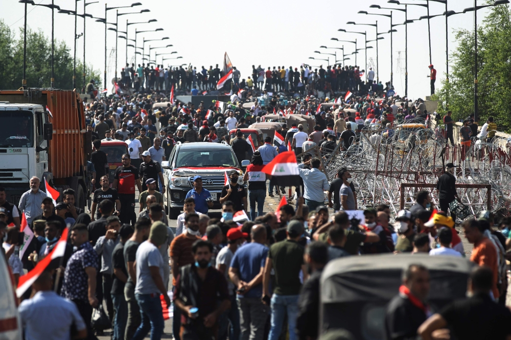 Iraqi protesters gather on the capital Baghdad's Al-Jumhuriyah Bridge on October 26, 2019, during an anti-government protest. Iraqi security forces fired tear gas to clear lingering protesters in Baghdad this morning, after dozens died in a bloody resumpt